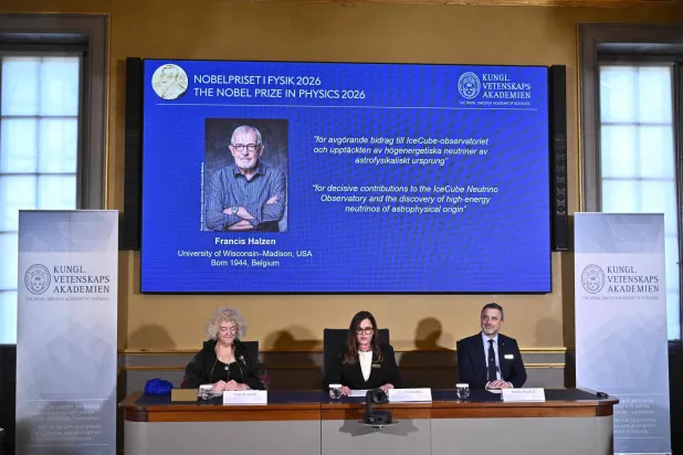 Eva Olsson, Ellen Moons, and Mark Pearce sit in front of a screen displaying Francis Halzen as the recipient of the 2026 Nobel Prize in Physics during a press conference at the Royal Swedish Academy of Sciences in Stockholm, Sweden, on October 6, 2026. (Photo by Christine OLSSON / TT NEWS AGENCY / AFP) 