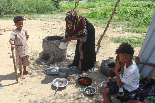 An internally displaced Yemeni woman cooks a meal for her children at a makeshift camp for the internally displaced who fled their homes due to renewed clashes between Yemen's government forces and the Houthi militants in the northern Hajjah governorate on October 7, 2026. (AFP)