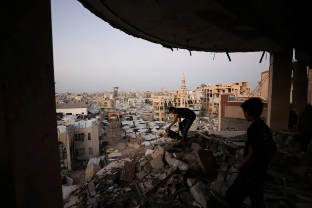 A Palestinian man works amid the rubble of a building damaged during the war, overlooking a makeshift tent camp at the Islamic University, in Gaza City, October 3, 2026. (Reuters) 