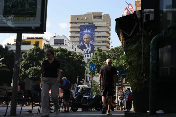 People walk past an election billboard showing Israeli Prime Minister Benjamin Netanyahu with the Hebrew phrase "We will not surrender" in Tel Aviv, Israel, 06 October 2026. (EPA)