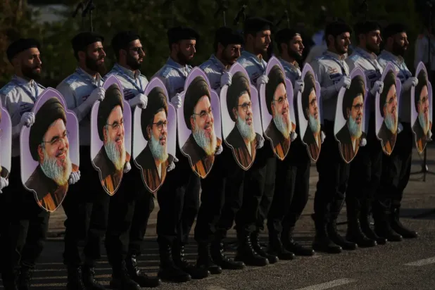Mehdi İzcileri, suikastlarının ikinci yıldönümünde, Hizbullah’ın eski Genel Sekreteri Hasan Nasrallah ile onun halefi olarak aday gösterilen Haşim Safiyuddin’in fotoğraflarını tutuyor. (AP)