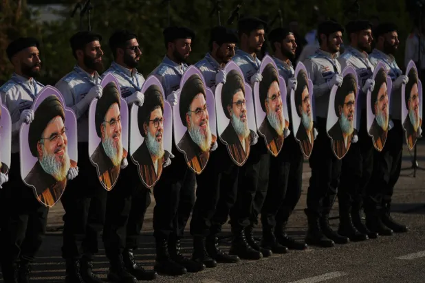 Members of Hezbollah's al-Mahdi Scouts hold portraits of Hezbollah leaders Hassan Nasrallah and his cousin and successor, Hashem Safieddine, during a gathering marking the second anniversary of their assassinations in Israeli airstrikes, in Dahiyeh, a southern suburb of Beirut, Lebanon, Sunday, Oct. 4, 2026. (AP Photo/Hassan Ammar)
