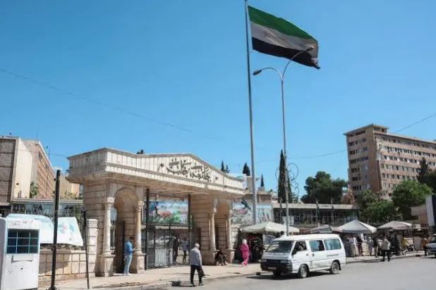 مارة قرب مدخل جامعة حلب والعلم السوري يوم 14 مايو 2025 (رويترز)