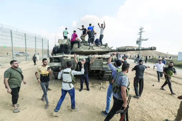 فلسطينيون في خان يونس يعتلون مركبة عسكرية إسرائيلية تم الاستيلاء عليها ضمن عملية «طوفان الأقصى» (د.ب.أ)