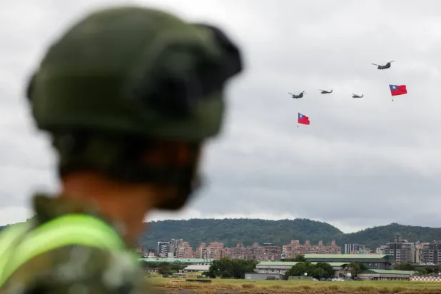 Bir Tayvan askerî personeli, Tayvan Ulusal Günü kutlamaları öncesindeki provalarda, dev Tayvan bayrakları taşıyan ABD yapımı iki 'Chinook' tipi helikopteri izlerken. - 6 Ekim (Reuters)