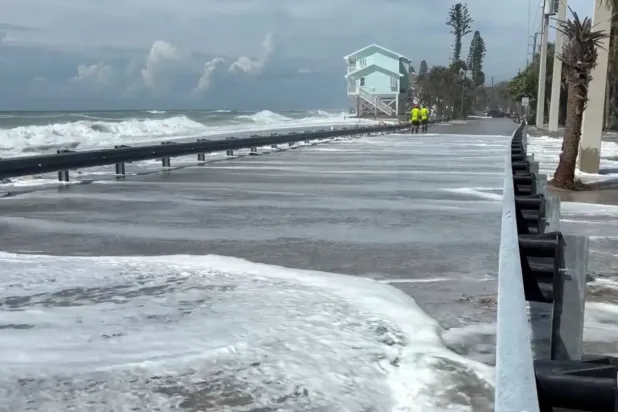 Florida'da Isaias Kasırgası yaklaşırken dalgaların yolu kapladığı sırada sahil yakınında yürüyen insanlar (Reuters)