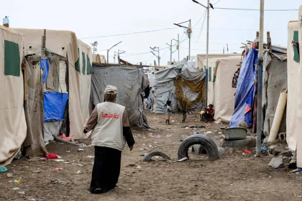 A relief worker walks among the tents at a temporary shelter for displaced people north of Aden (AFP)