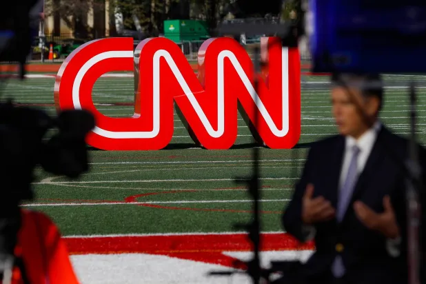 صحفي يسجل مقطع فيديو بالقرب من لافتة لشبكة "سي إن إن" (CNN) (أ.ب)
