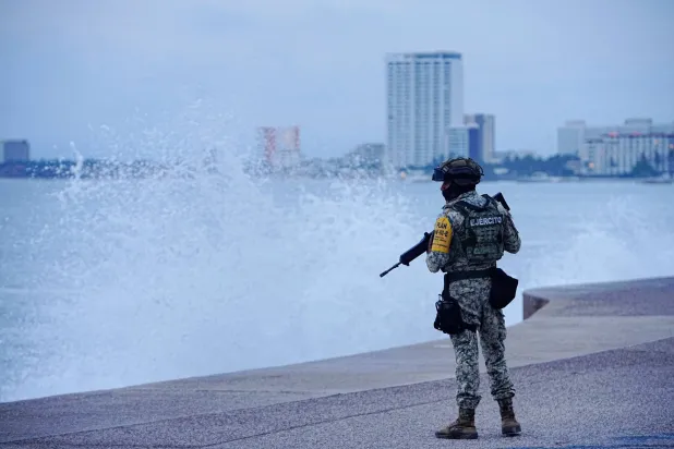 A member of the Mexican Army stands on the Malecon waterfront during the implementation of Plan DN-III-E, a disaster relief plan, as waves crash ashore ahead of Hurricane Simon in Puerto Vallarta, Mexico, October 10, 2026. REUTERS/Christian Ruano
