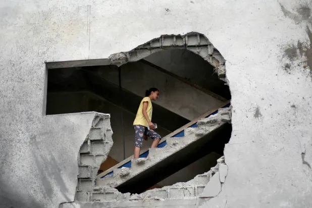 فتاة فلسطينية تصعد درجاً في مبنى مدمر استُهدف بغارات جوية إسرائيلية بمنطقة الزوايدة وسط قطاع غزة الأحد (أ.ف.ب)