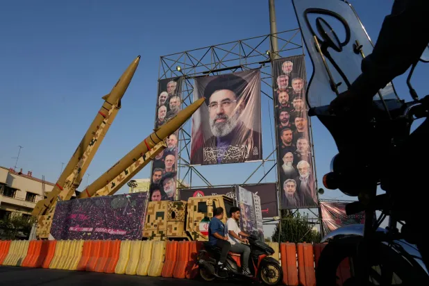 Motorbikes drive past Iranian missiles and banners showing portraits of the Iranian Supreme Leader, Mojtaba Khamenei, center, and the late armed forces commanders and nuclear scientists, who were killed in Israeli and US strikes, displayed in a military exhibition commemorating the anniversary of the start of the 1980-88 Iraq-Iran war at Baharestan Square, in Tehran, Monday, Sept. 28, 2026. (AP Photo/Vahid Salemi)