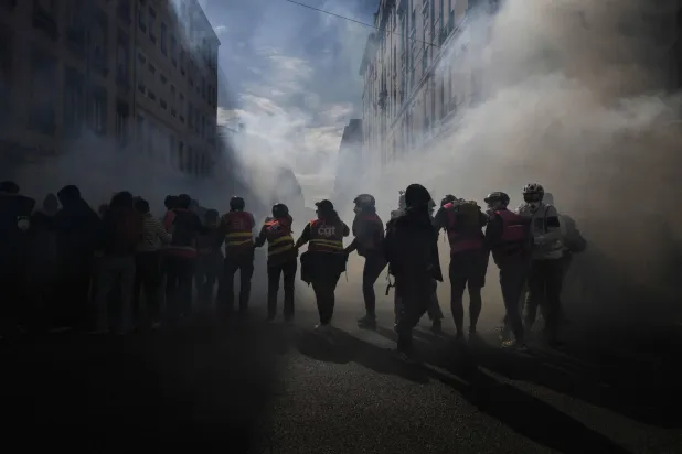 CGT unionists stand amid tear gas fired by riot police during a demonstration of high-school students in Lyon, southeastern France on October 13, 2026, as part of a nationwide high school mobilization. (AFP)
