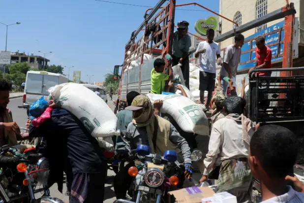 Husilerin kuşatması altındaki Taiz’de bir grup kişi, kamyondan buğday unu indiriyor (Reuters)