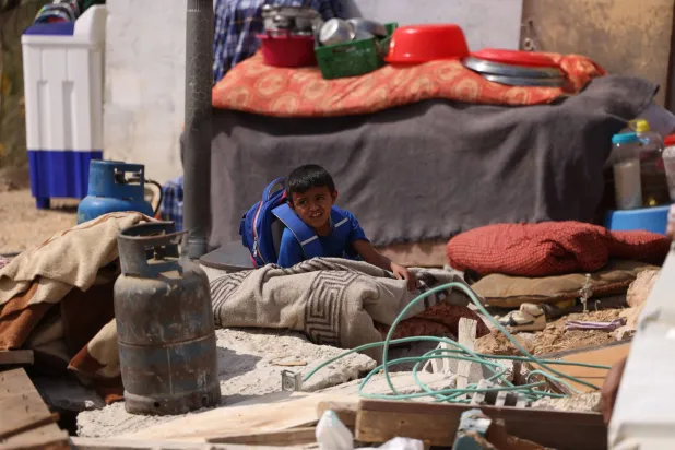 A boy sits amid belongings next to a structure used as a living room after it was demolished by Israeli authorities, who said it had been built without a permit, in the Palestinian village of Umm al-Khair, in the Israeli-occupied West Bank, on October 14, 2026. (Photo by HAZEM BADER / AFP)