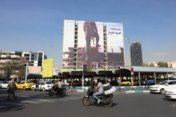 İranlılar, 14 Ekim 2026’da Tahran’daki Venek Meydanı’nda ABD karşıtı bir reklam panosunun önünden araçlarıyla geçiyor (AP)