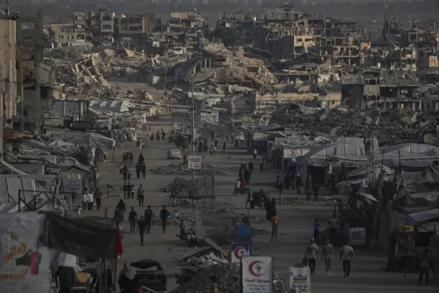 Gazze şehrinde yıkılmış binaların arasında yürüyen Filistinliler (AP)