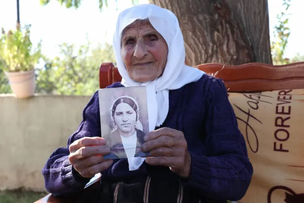 The 117-year-old Qamile Marra holds a black and white photograph from her youth during an interview with AFP in the garden of her home in the village of Ferras, near Kucove, some 80 kilometres from the capital Tirana on October 3, 2026. (Photo by Adnan Beci / AFP)