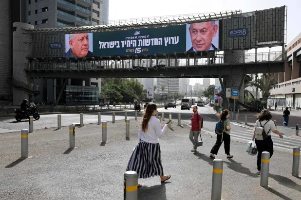 People walk past a banner featuring Israel's Prime Minister Benjamin Netanyahu (R) of the Likud party and country's former chief of the general staff and leader of the Yashar centrist political party Gadi Eisenkot in Ramat Gan on October 15, 2026. (AFP) 