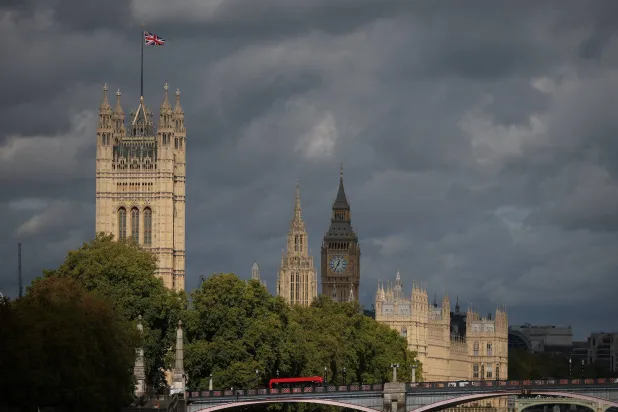A red double-decker bus rides past as a Union Jack flag flutters on the Victoria Tower at the Houses of Parliament in London, Britain, October 15, 2026. REUTERS/Isabel Infantes