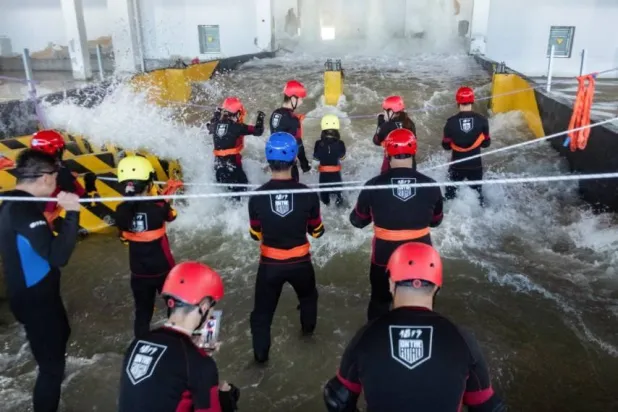 Participants brace for surging water in a flash flood simulator at the Lvxing center in Hangzhou (Reuters)