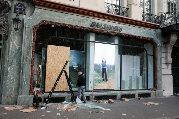 Paris’te hayat pahalılığı ve akaryakıt fiyatlarındaki artışı protesto eden ülke çapındaki gösterilerin ertesi günü çıkan çatışmalarda zarar gören Salomon mağazasının vitrinini onaran bir kişi (Reuters)
