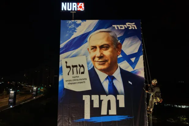 Rappelling workers install an election billboard featuring an image of Israeli Prime Minister Benjamin Netanyahu, and reading in Hebrew "It's either the Right or Palestine," in Ramat Gan near Tel Aviv, Israel, 18 October 2026. (EPA)