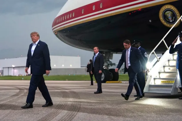 ABD Başkanı Donald Trump, cumartesi günü Florida’ya başkanlık uçağıyla varmasının ardından konvoyuna doğru ilerliyor. (AP)