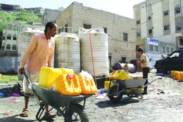 Yemenliler, Taiz kentinde bir yardım kuruluşuna ait depodan içme suyu alıyor. (Arşiv-Reuters)