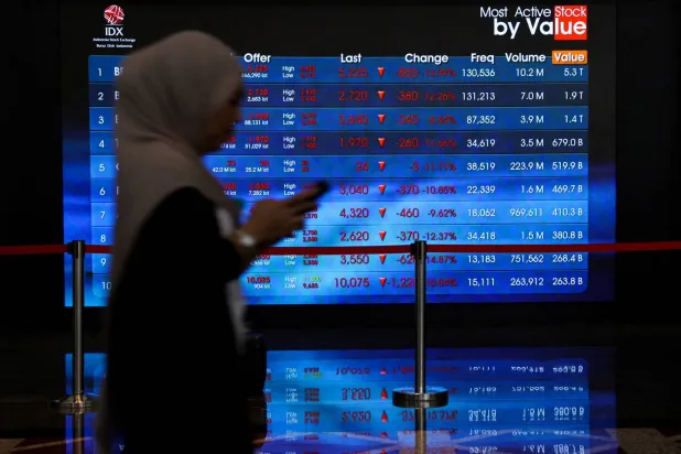 عاملة تمرّ أمام لوحة إلكترونية تعرض تحركات الأسهم ببورصة إندونيسيا في جاكرتا (رويترز)