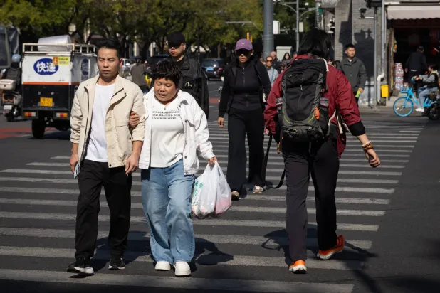 People cross the street at a busy intersection in Beijing, China, 19 October 2026. (EPA)