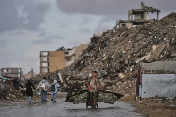  A Palestinian man carries metal sheets past the ruins of buildings destroyed during the Israel-Hamas war in Gaza City, Sunday, Oct. 18, 2026. (AP) 