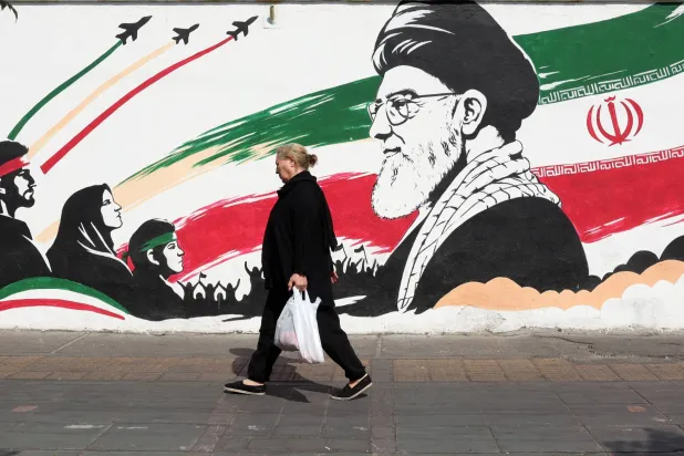 An Iranian woman walks past a mural of late Iranian Supreme Leader Ali Khamenei on a street in Tehran, Iran, 14 October 2026, amid the ongoing conflict between Iran and the United States. (EPA)