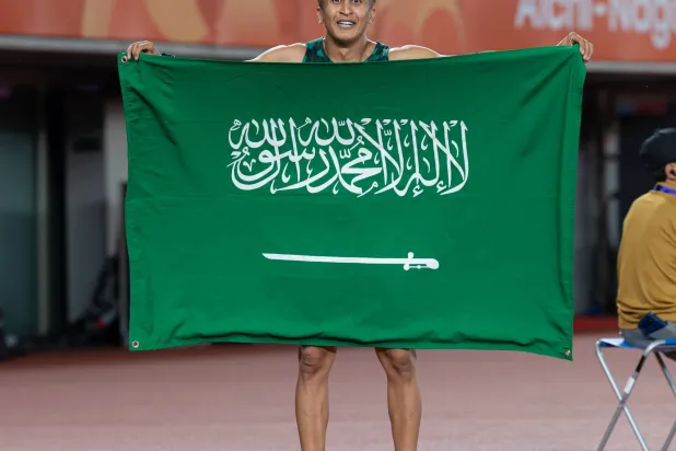 السعودي ثامر الزهراني حاملاً علم بلاده ومحتفلاً بالإنجاز (فريق السعودية)
