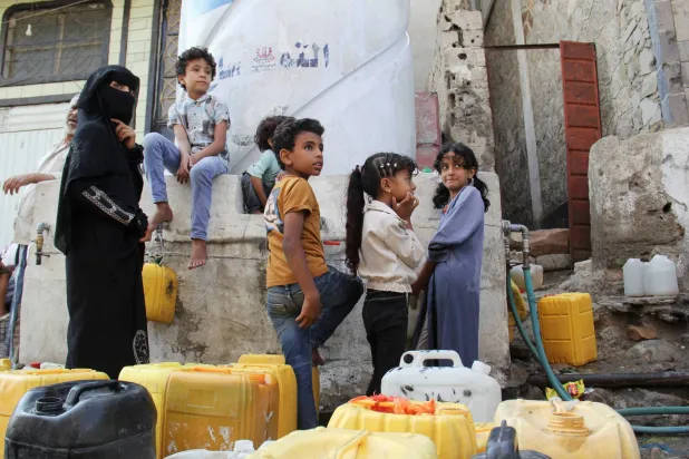  A woman and children wait to fill jerrycans with drinking water from a charity tank in the southwestern city of Taiz, Yemen, October 20, 2026. (Reuters)