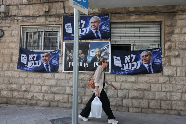 A woman passes by an election billboard of Israeli Prime Minister Benjamin Netanyahu with Hebrew slogan reading "will not surrender" in Jerusalem, 21 October 2026. (EPA)