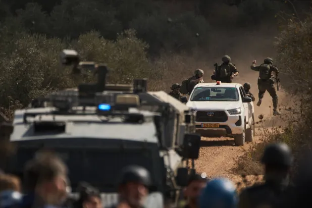 قوات إسرائيلية تصل إلى طريق مغلق يمنع الفلسطينيين من الوصول إلى بساتينهم لقطف الزيتون في بلدة ترمسعيا بالضفة الغربية يوم الأربعاء (أ.ب)