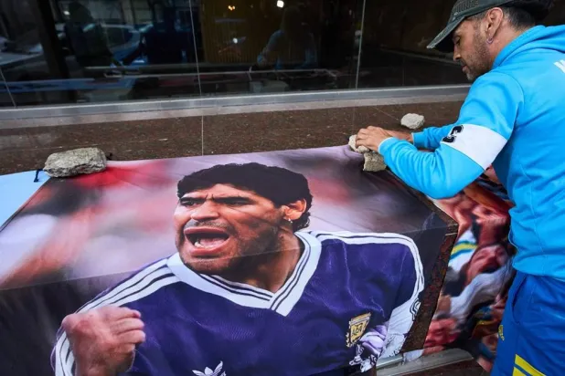  A fan of Diego Maradona displays his image outside the court where a trial is ongoing for the medical team that treated Maradona facing charges of alleged homicide by negligence, in San Isidro in Buenos Aires, Argentina, Wednesday, Oct. 21, 2026. (AP) 