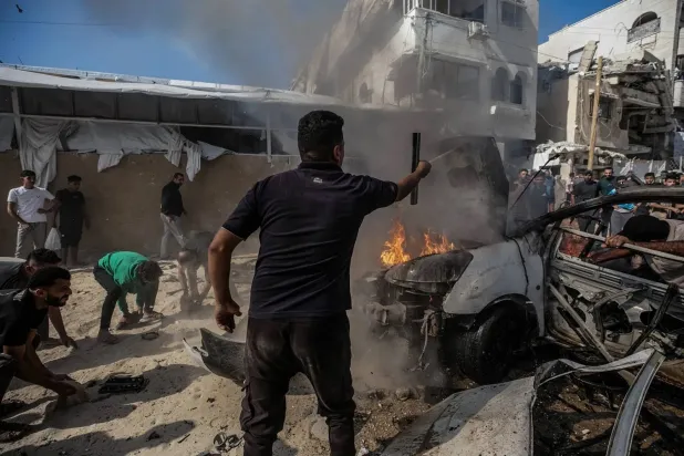 Palestinians try to extinguish a fire in a vehicle destroyed by an Israeli airstrike south of Gaza City on Thursday. (EPA)