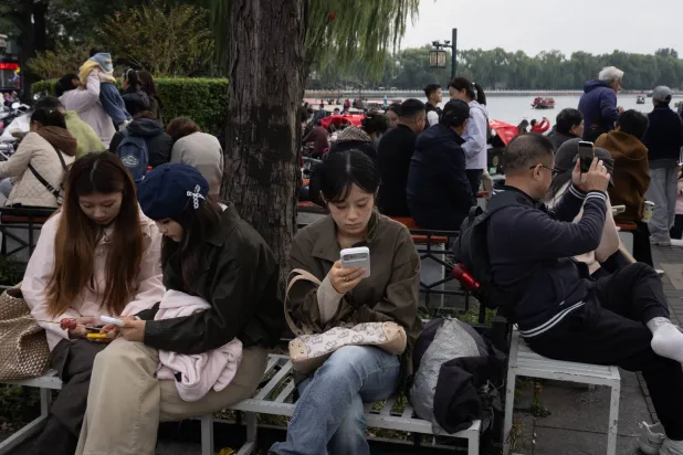 People look at their phones in a touristic area in Beijing, China, 22 October 2026. (EPA)