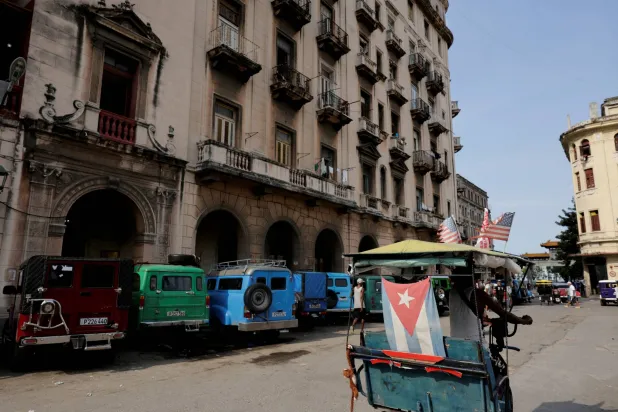 FILE PHOTO: A man rides a bicycle taxi past parked vintage cars normally used for public transportation, in Havana, Cuba, July 21, 2026. REUTERS/Norlys Perez/File Photo