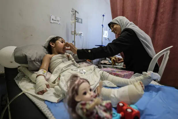 فلسطينية تهتم بطفلة تتلقى العلاج من حروق أصابتها إثر هجوم إسرائيلي على مبنى سكني قتل والديها بمدينة غزة في 15 أكتبر 2026 (د.ب.أ)