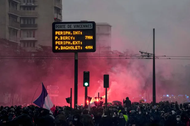 Protesters light flares at the Porte de Vincennes during a demonstration in favor of purchasing power, the protection of public services, and fiscal and social justice, in Paris on October 24, 2026. (Photo by Dimitar DILKOFF / AFP)
