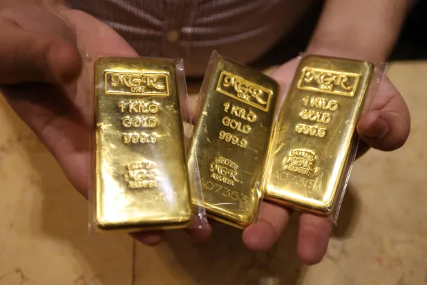 بائع يعرض سبائك ذهبية في متجر مجوهرات داخل سوق الذهب في السوق القديمة بدبي (إ.ب.أ)