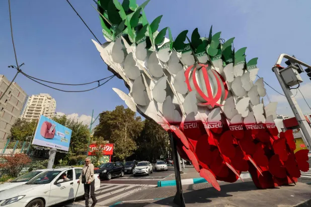  Traffic moves past an installation depicting butterflies forming the Iranian national flag in Tehran on October 21, 2026. (AFP) 