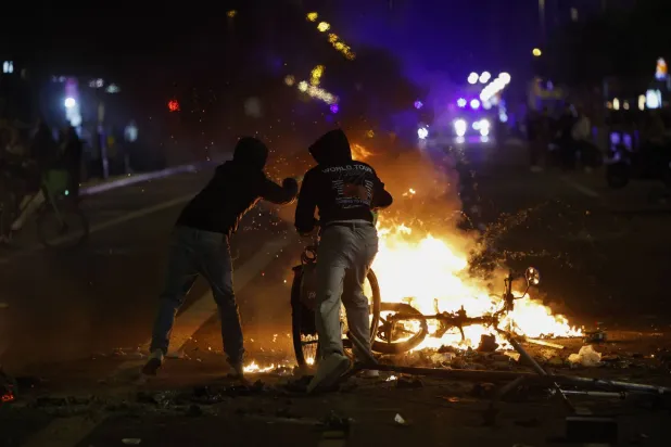 أشخاص يحرقون أغراضاً فوق متراس بأحد الشوارع خلال اشتباكات بين محتجين والشرطة وذلك في احتجاج نظمه طلاب في ساحة كاتالونيا بمدينة برشلونة الإسبانية (إ.ب.أ)