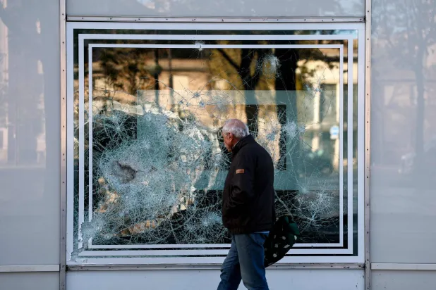 A pedestrian walks past a broken window, a day after a demonstration in favor of purchasing power, the protection of public services, and fiscal and social justice, in Paris on October 25, 2026 as part of a nationwide call for mobilization bringing together former members of the Yellow Vest movement, labor unions, high school and university students. (AFP) 