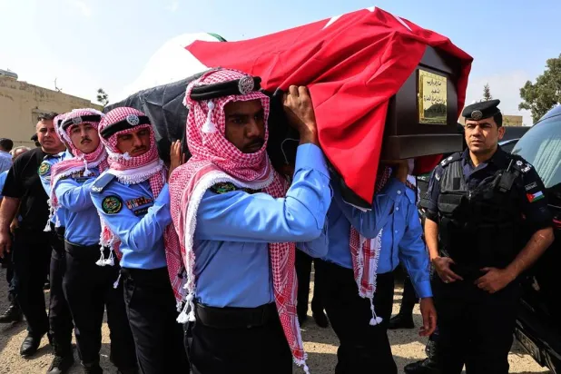  Jordanian honor guards carry a flag-draped coffin of on of the victims killed in an attack on a Greek Orthodox church during their funeral procession in Karak, Jordan, Sunday, Oct. 25, 2026. (AP) 