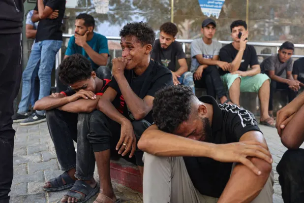 Mourners grieve during the funeral of three Palestinians at Al Shifa Hospital in Gaza City on October 25, 2026, after they were killed in an Israeli strike on the Islamic University building. (AFP)
