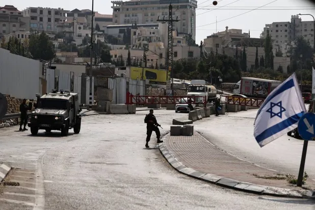 Israeli soldiers stand guard at a closed military gate at an entrance to the West Bank city of Hebron, 25 October 2026, as the military enforced a closure on the city and surrounding villages for a third consecutive day. (EPA)