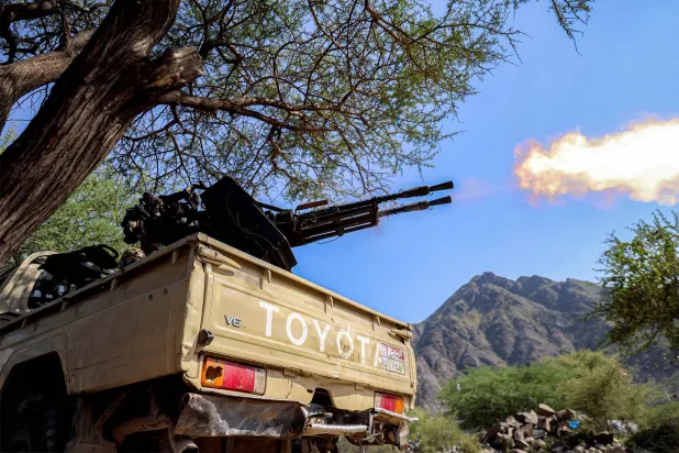 A fighter loyal to Yemen's internationally-recognized government fires a turret from the back of a pickup truck at a position along the frontlines against the Houthis around Mount al-Midan in Yemen's western Taiz province on October 26, 2026.  (Photo by Ahmad AL-BASHA / AFP) / 